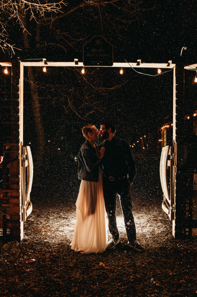 Couple kiss at night as snow falls around them at Forest City Brewery.