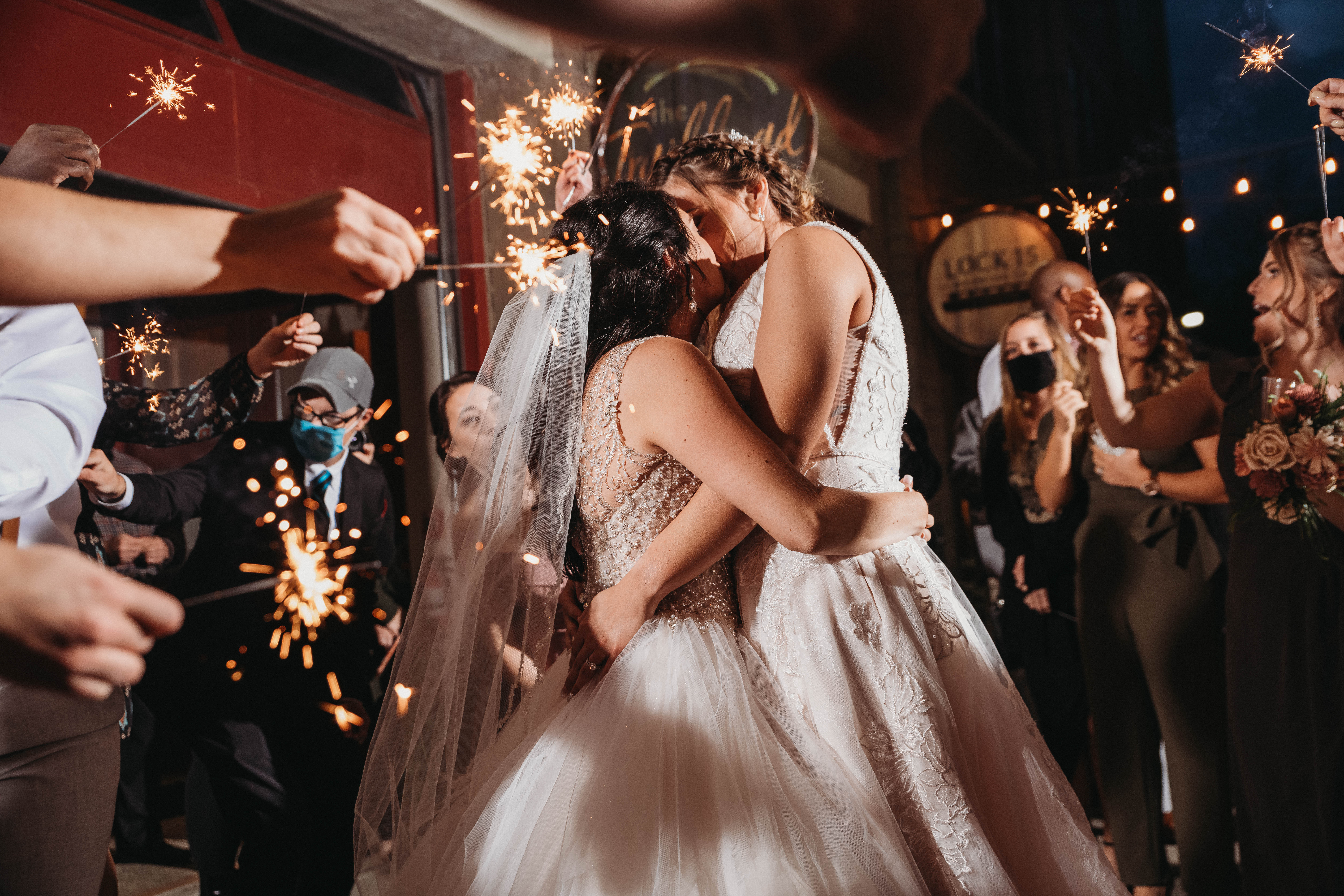 Brides kiss at the sparkler exit of their LGBTQ friendly wedding.