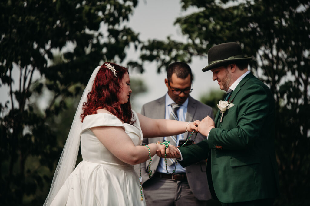 Couple handfasten with a irish rope at their ceremony at Cox Arberateum.