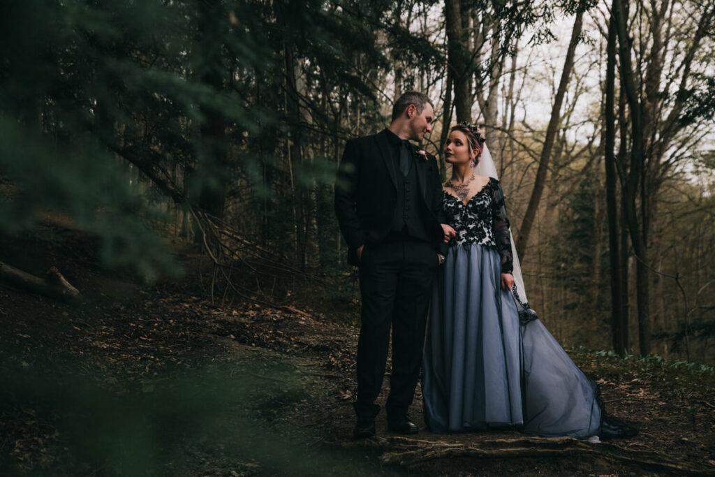 Gothic couple in woods, bride wearing black wedding dress.