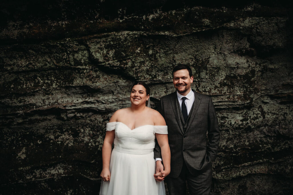 Bride and Groom smile at mossy ledges on their elopement day in Ohio park.
