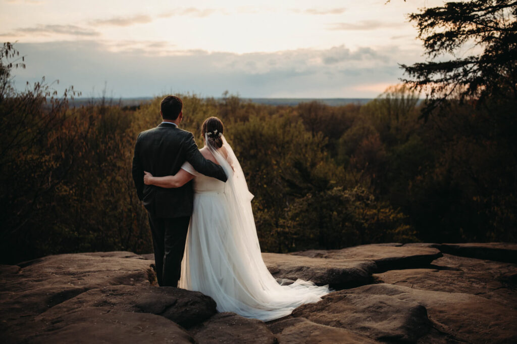 Couple stand on ledge in Cuyahoga Valley National Park at Sunset.