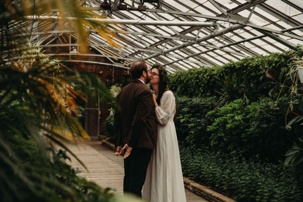 Newlyweds kiss in private moment at ROckefellar Park greenhouse Wedding.