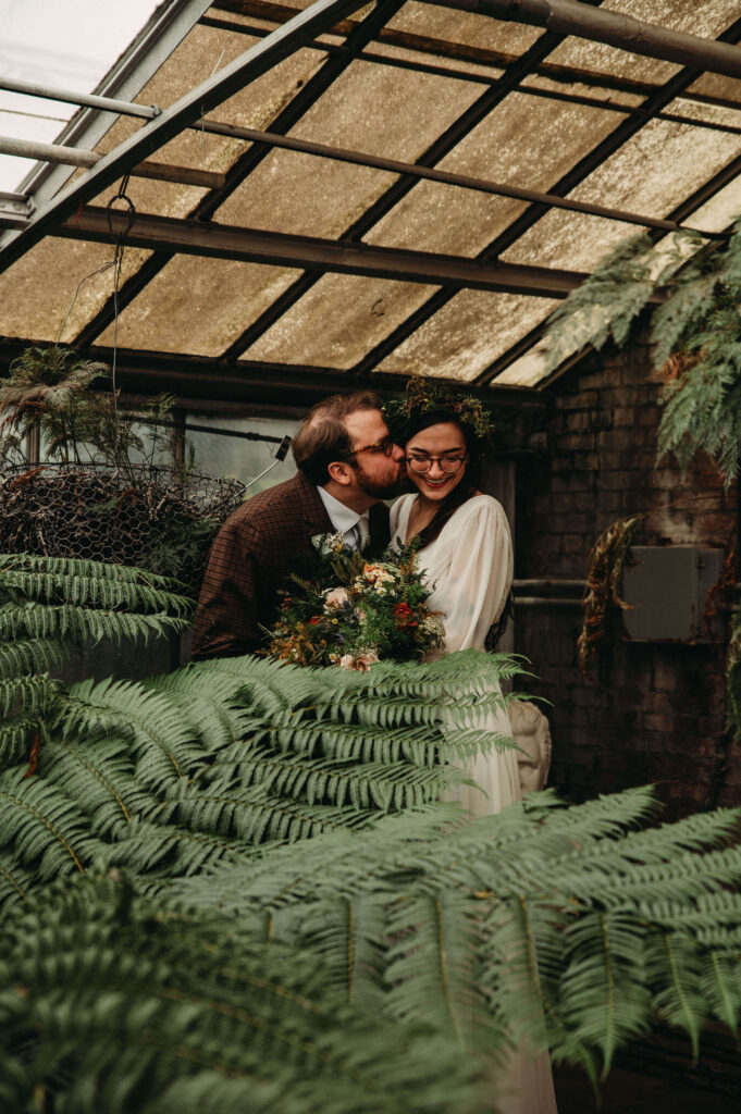 Couple are surrounded by foliage at greenhouse wedding in CLeveland.