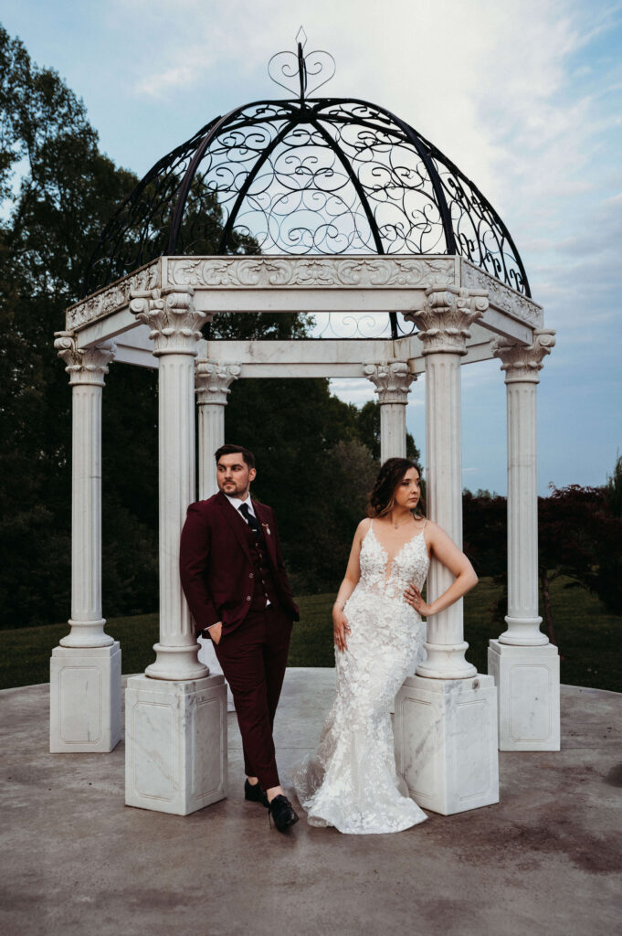 Couple pose in serious style at marble gazebo at sunset at Bella Amore.