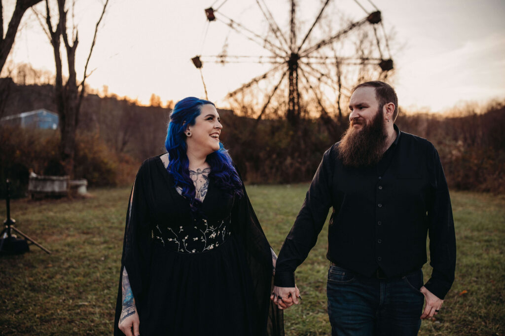 Laughing couple walk in front of abandoned ferris wheel in West Virginia.