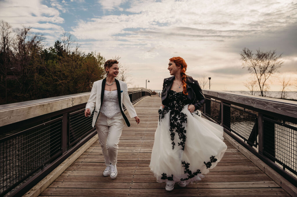 In Local Cleveland park trans couple laugh and run toward camera on wedding day.