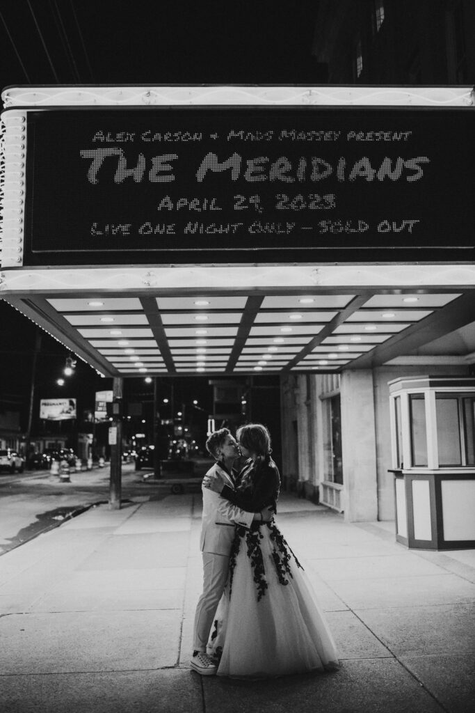 Couple kiss under marquis at laSalle Theatre for their punk themed wedding.