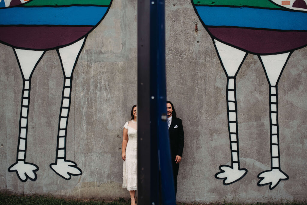 Unique and fun pose of bride and groom against Love Birds Mural in Ohio City.