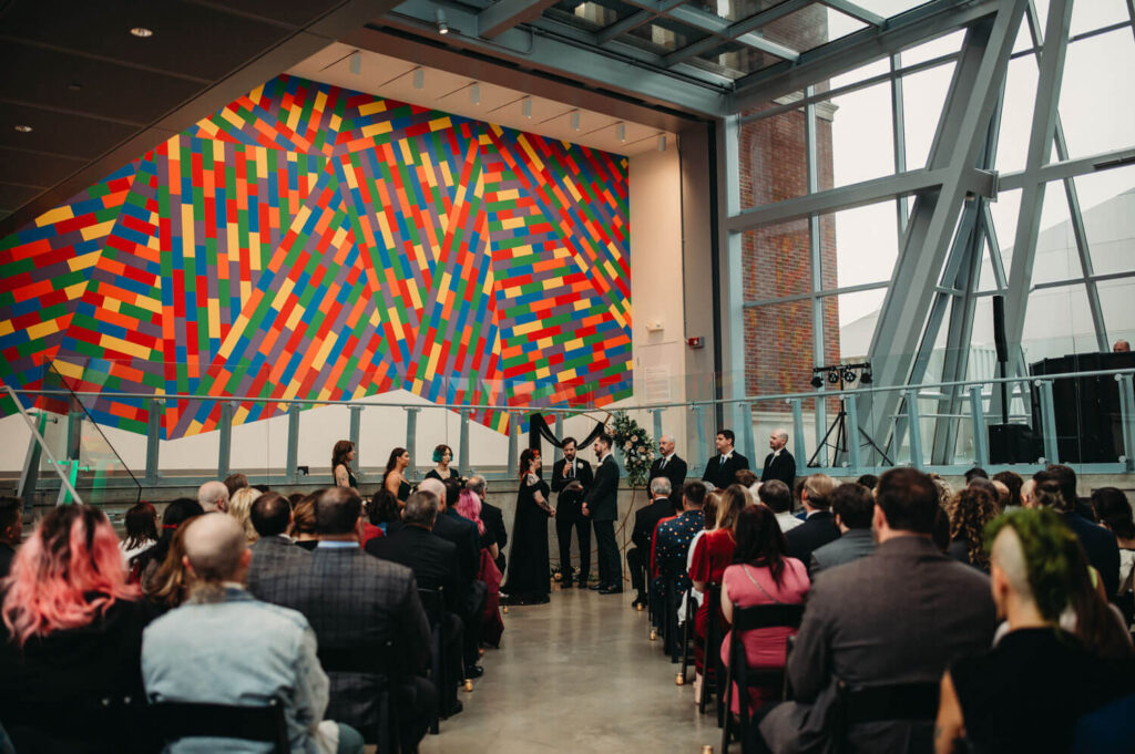 Ceremony held in front room of Akron Art museum by colorful wall.