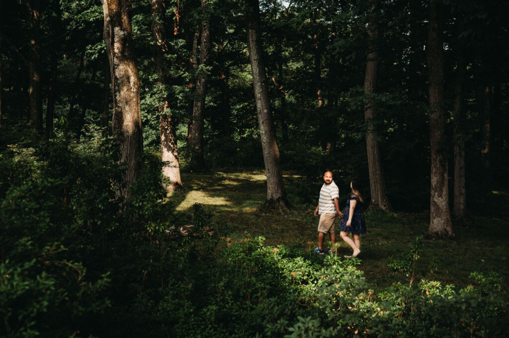 Engaged couple walk through forest in Holden Arboreteum near Cleveland