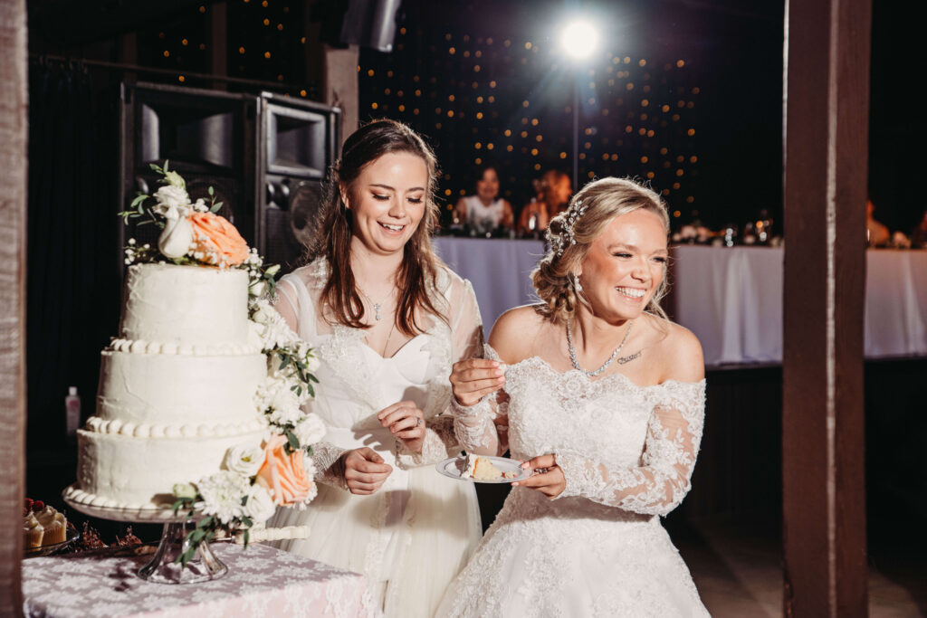 Two brides celebrate thier wedding as they cut the cake in a lodge wedding venue.