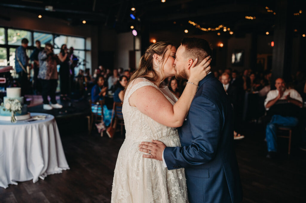 Couple kiss at first dance on floor of Music Box wedding in the Flats.