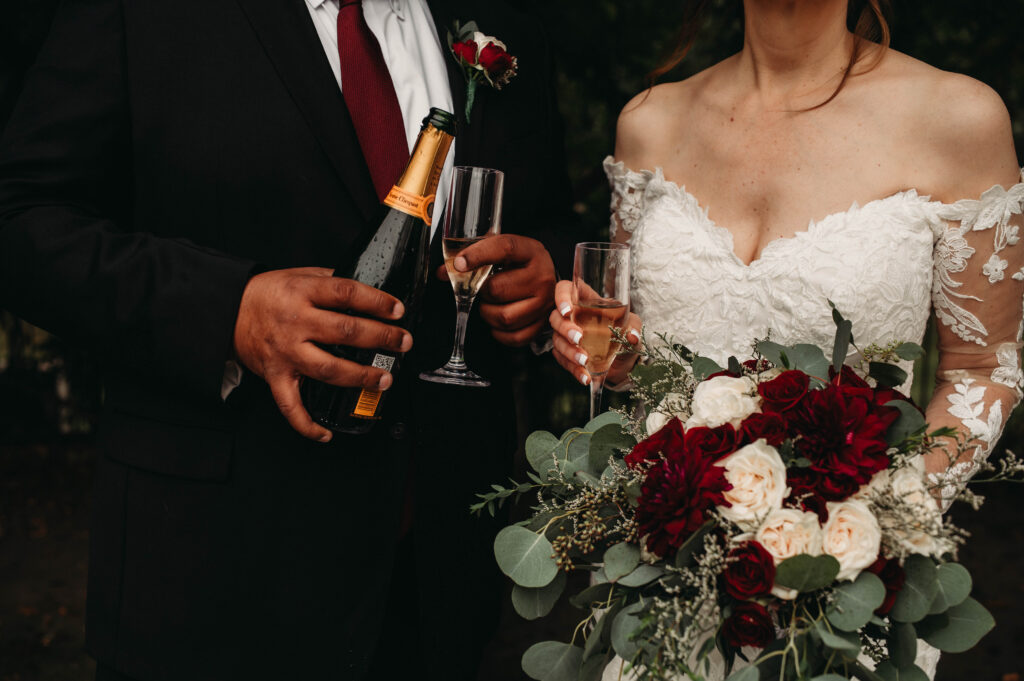Hands hold champagne for classic dressed wedding couple.