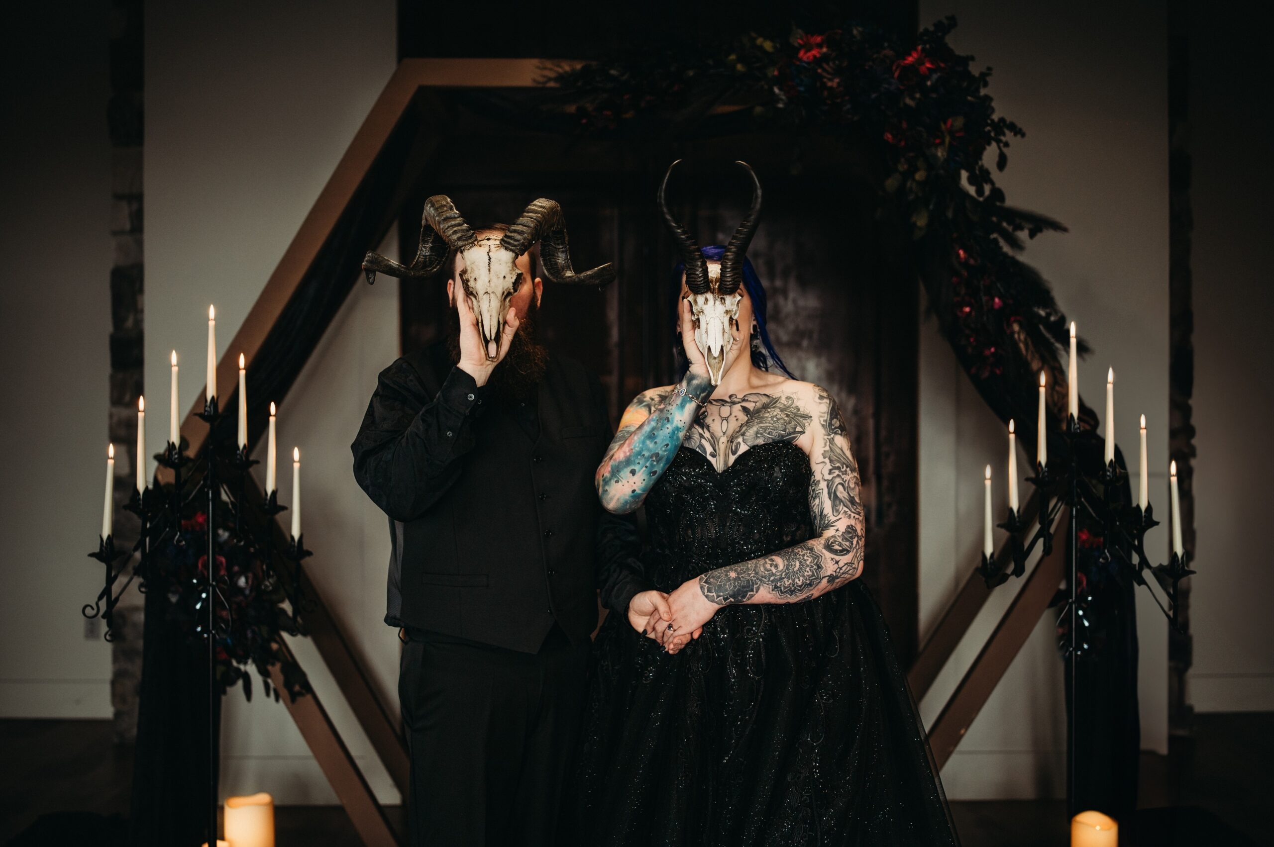 Couple hold skulls in front of face for their gothic wedding day.