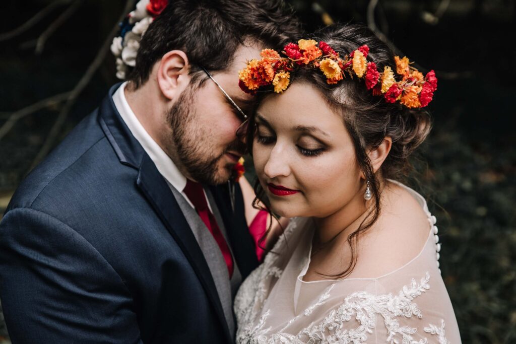 Bride with flower crown snuggles with groom at Festival.