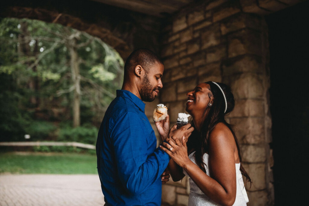 Couple share cupcakes after eloping at a medieval building.