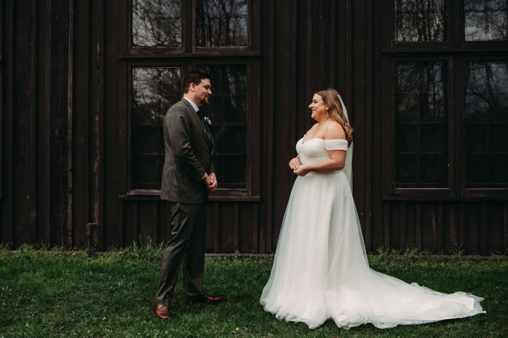 Couple share first look in front of rustic building in spring wedding.
