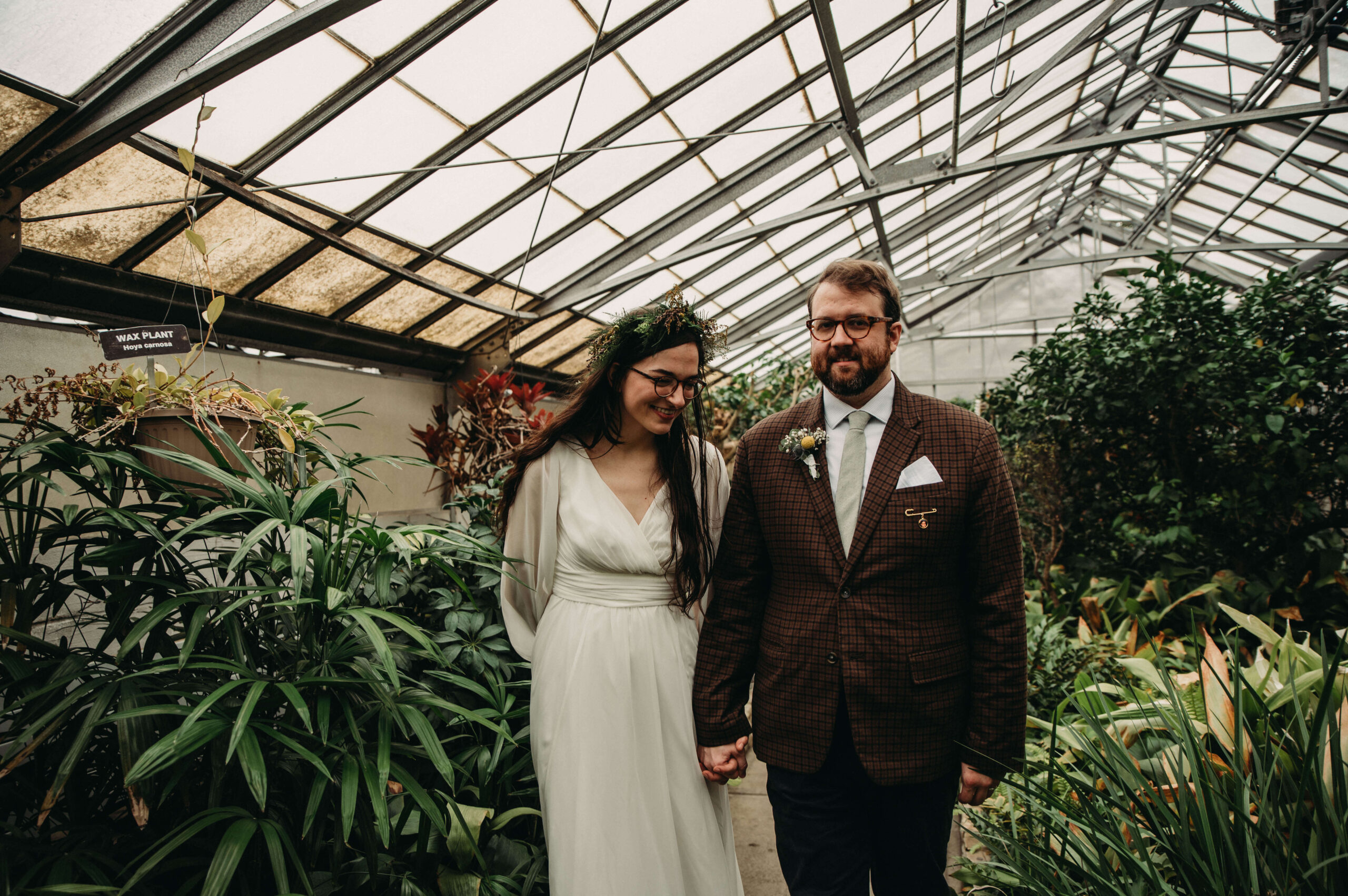 Rockefellar greenhouse wedding features boho vintage couple walking through aisle.