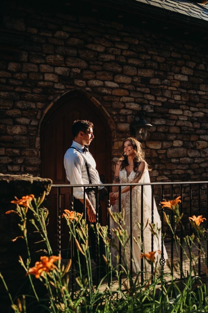 Couple stand outside of castle during golden hour.