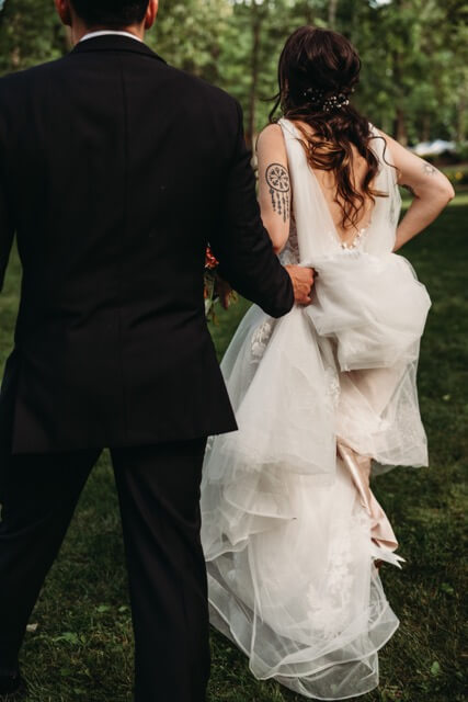 Groom holds dress, bride shows off nordic inspired tattoo for geeky wedding.
