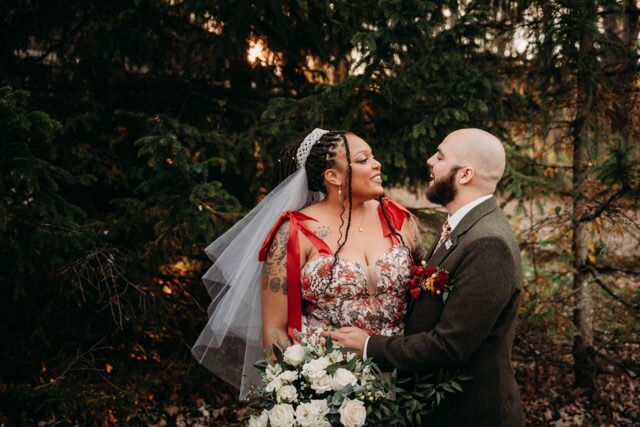 Newlyweds laugh among woods in cottage aesthetic venue.