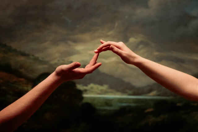 Close up of hands against painted art piece at museum.