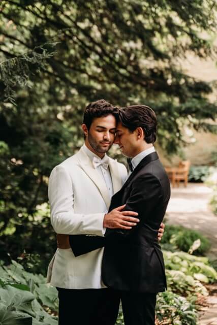 Sweet moment between grooms at fellows riverside garden