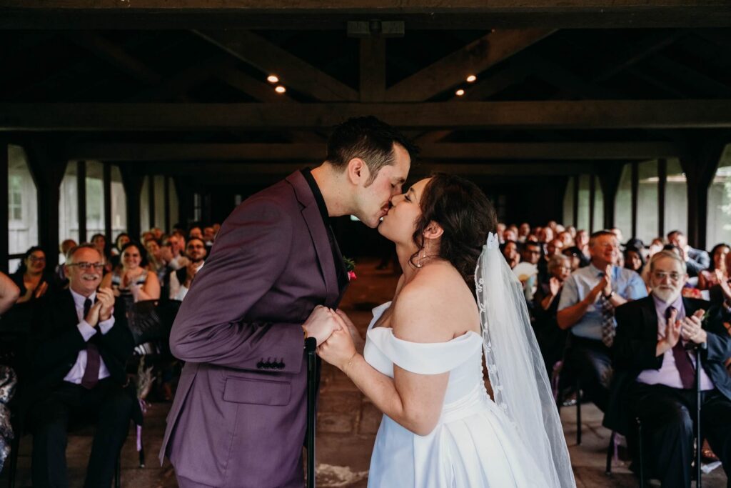 Ceremony kiss from officiant's point of view in the screened in room at happy days lodge.