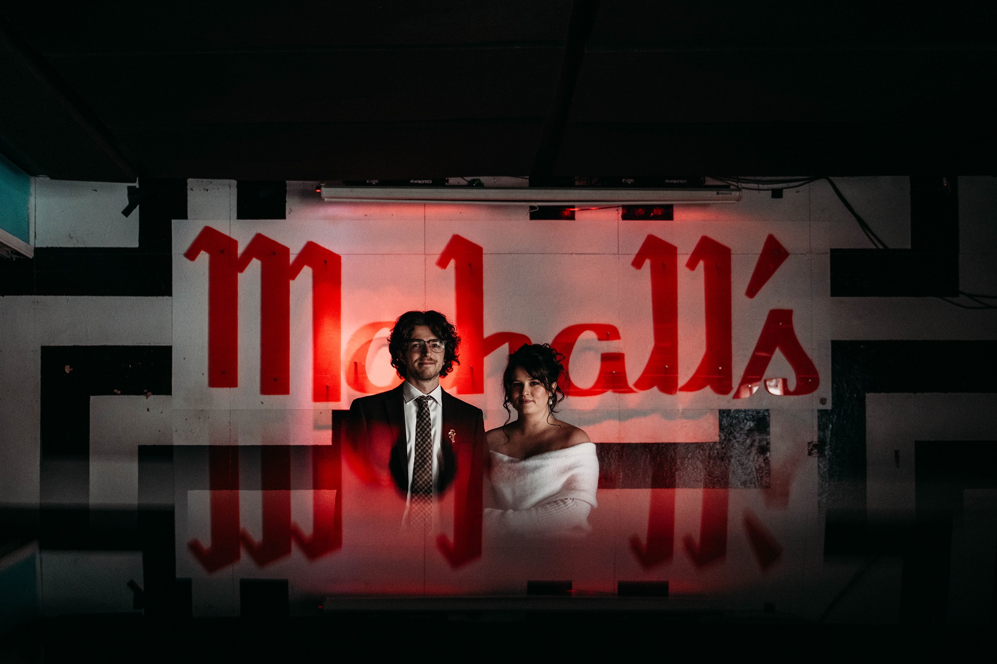 Couple stands in Mahalls room for moody portrait