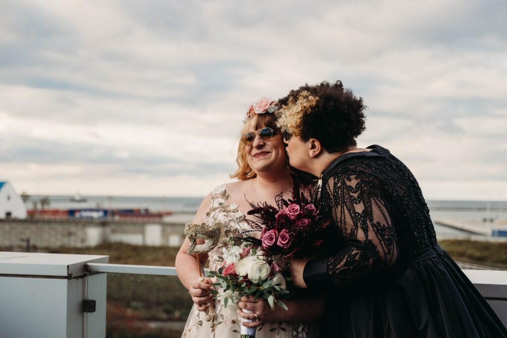 Brides share a sweet cheek kiss on the balcony at Lago in Cleveland.